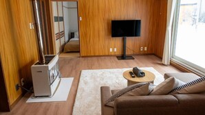 A modern living room with a wooden interior, a flat-screen TV, a sofa, a coffee table, and a fireplace. - FURANO RELAX STAY A (Furano)