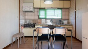 A compact kitchen with a dining area, featuring a stove, sink, and a window with blinds. - FURANO RELAX STAY A (Furano)