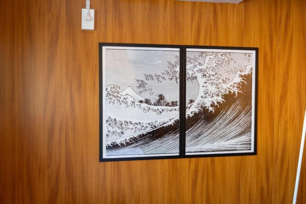 A wooden wall with two framed artworks depicting a wave and a mountain.