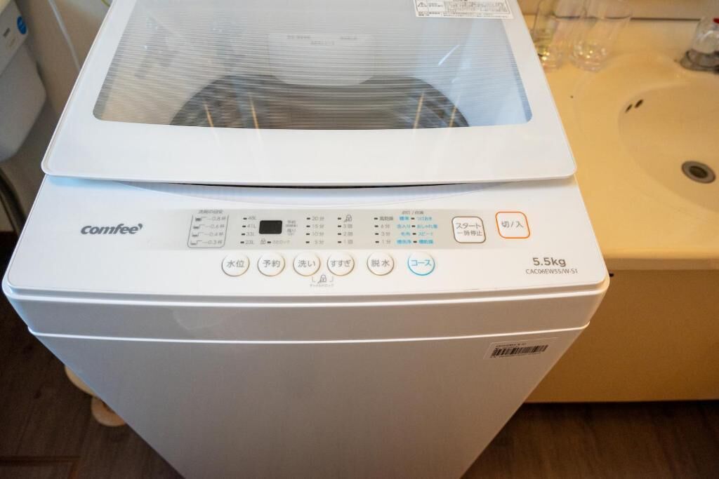 A white Comfee washing machine with a control panel, a 5.5kg capacity label, and a transparent door.