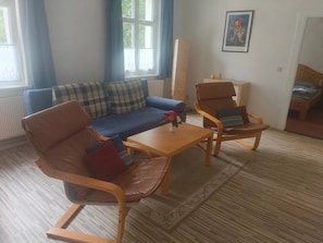 Una sala de estar con un sofá, dos sillones, una mesa de centro y un cuadro en la pared.