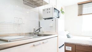 A modern kitchen with a sink, cabinets, and a small refrigerator. There is a bed with a sign indicating extra bedding. - Close to Meguro Station 1Room Studio with full facilities, convenient transportation, 2 stops to Shibuya, mid to long term stay is welcome! (目黒区)