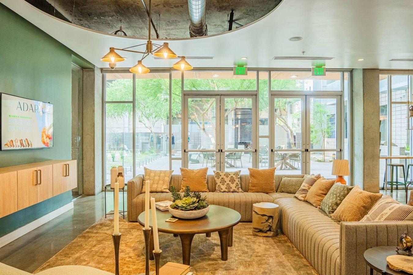 A modern lounge area with a sofa, a round table, and a coffee table, featuring a view through large windows.
