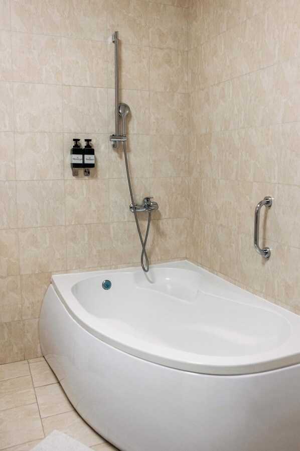 Un baño moderno con una bañera independiente, un cabezal de ducha de mano y un pasamanos.
