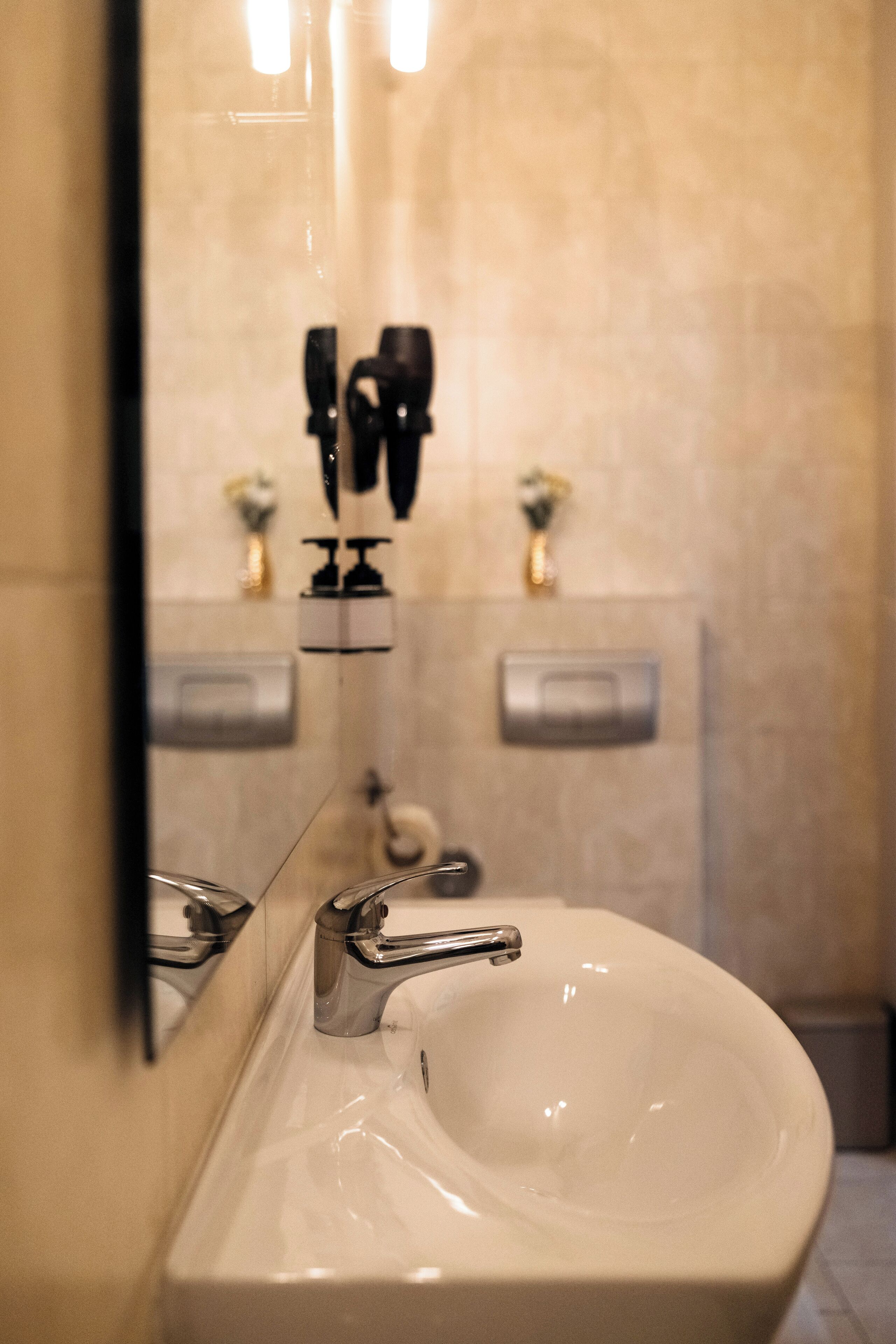 A bathroom with a white sink, a mirror, and a towel dispenser.