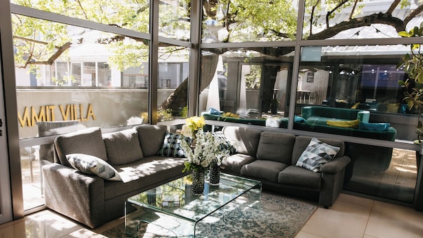 Una sala de estar moderna con una mesa de centro de vidrio, dos sofás grises y un amplio ventanal con vistas al exterior.