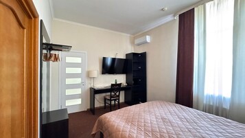 Habitación de hotel con cama, escritorio, silla, televisor y armario.