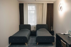 A room with two single beds, a desk, a chair, a nightstand, and a window with curtains. - Summit Villa Chisinau (Chișinău)
