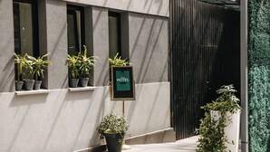 Una entrada de hotel moderna con plantas en macetas y un letrero.