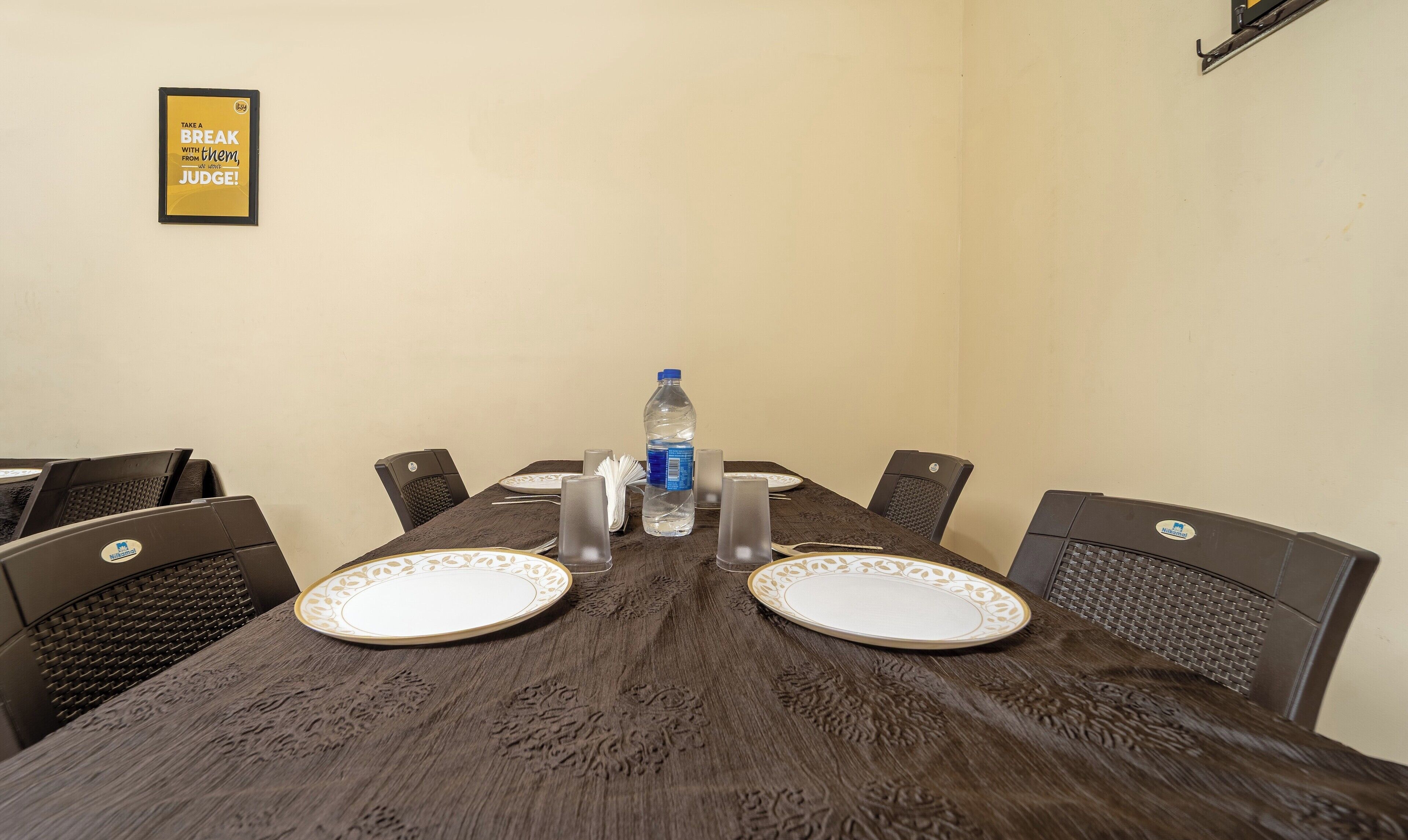 A conference room with a wooden table, two chairs, a water bottle, and a framed quote on the wall.