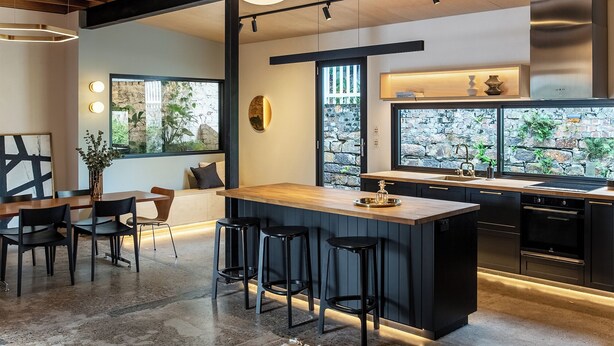 Een moderne keuken met een centraal eiland, barstoelen en een eethoek met een tafel en stoelen.