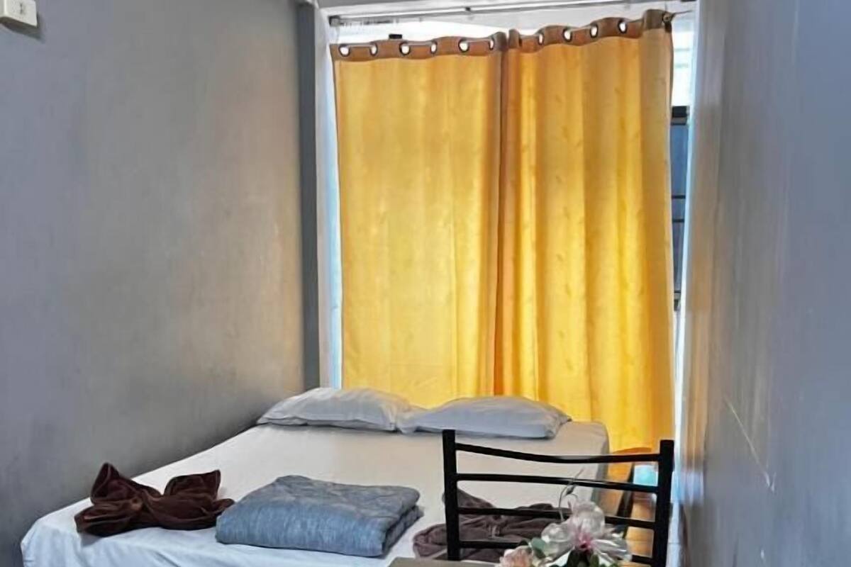A small, compact room with a single bed, a wooden table, and a chair.