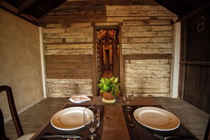 A rustic wooden dining area with a table set for two, a potted plant, and a wooden door in the background. - Eladetta Retreats  (Kandy)