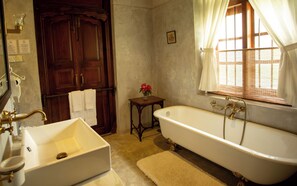A bathroom with a bathtub, a sink, and a wooden door. - Eladetta Walauwa Kandy (Kandy)