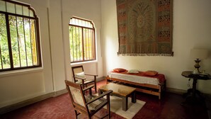 A room with a bed, a chair, a table, and a large tapestry on the wall. - Eladetta Retreats  (Kandy)