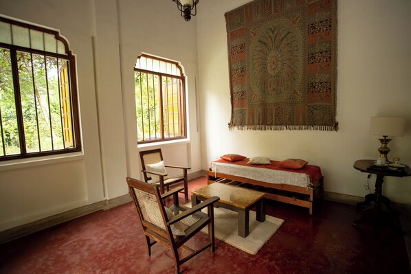 A room with a bed, a chair, a table, and a large tapestry on the wall. - Eladetta Walauwa Kandy (Kandy)