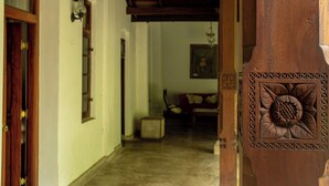 A wooden door with intricate carvings, a hallway leading to a room with a chair and a painting on the wall. - Eladetta Retreats  (Kandy)