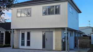 Een gebouw met twee verdiepingen, een plat dak, grote ramen en een bakstenen fundering.