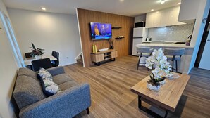 Een moderne woonkamer met een bank, een salontafel en een televisie bevestigd aan een houten wand.