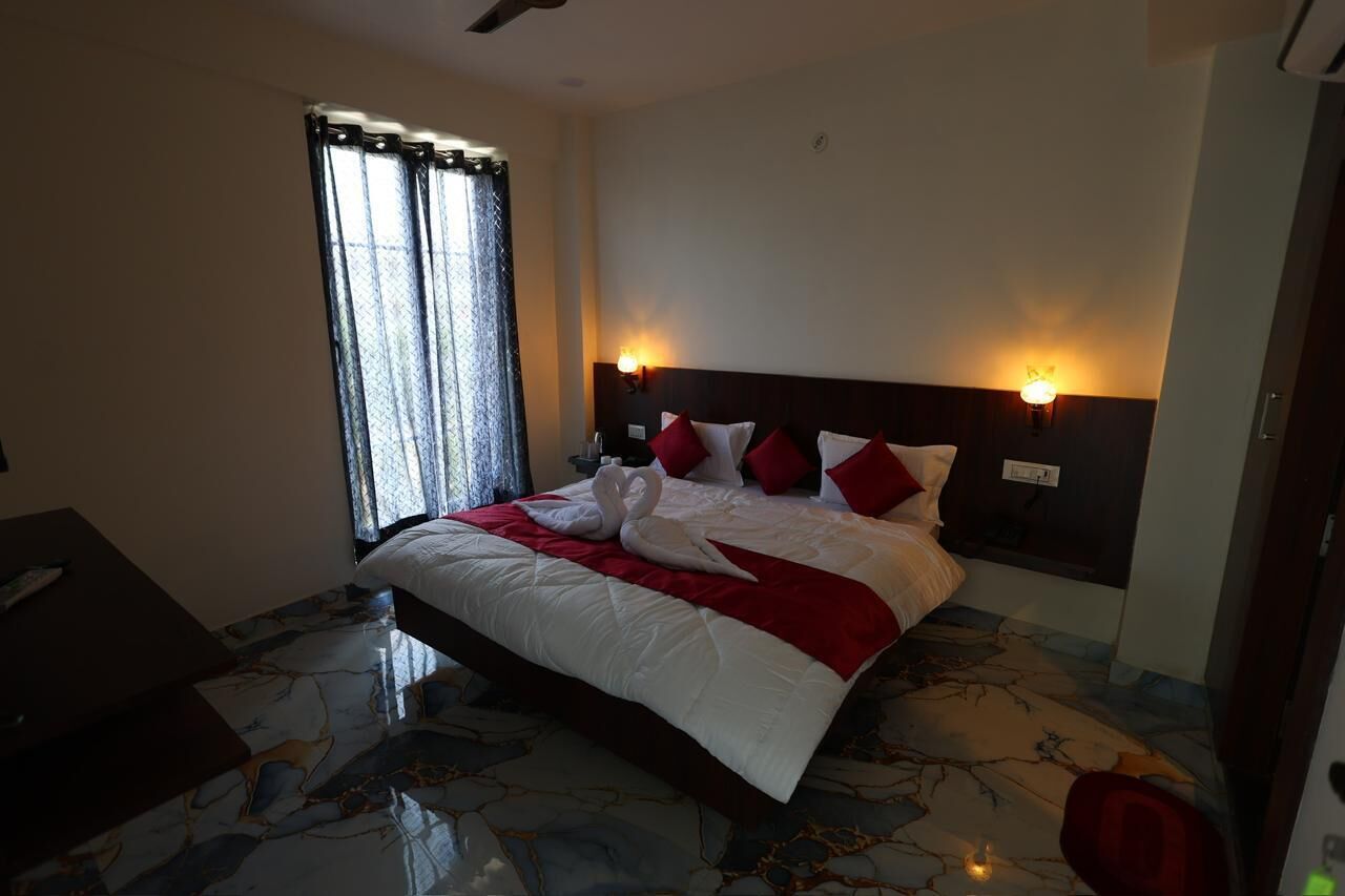 Quarto de hotel com uma cama, mesa de cabeceira, abajur e janela com cortinas.