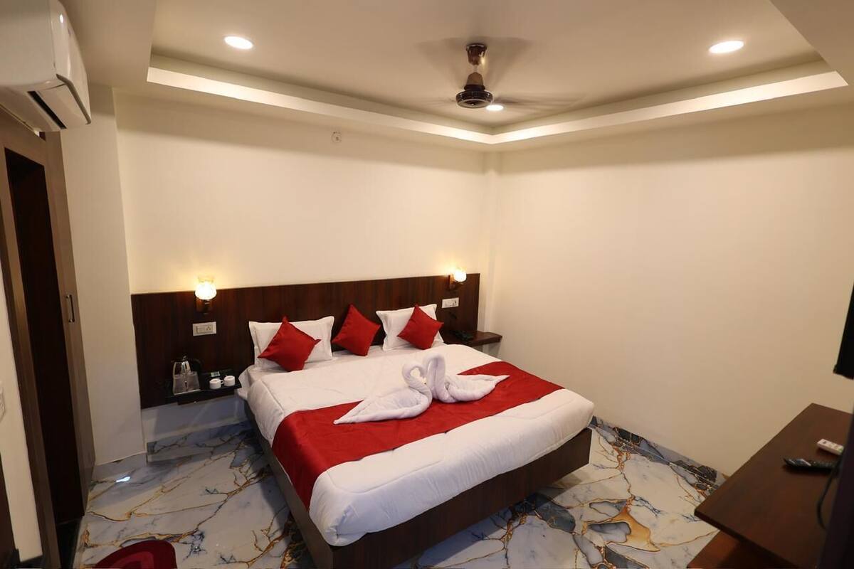 A hotel room with a bed, a nightstand, a TV, and a ceiling fan.