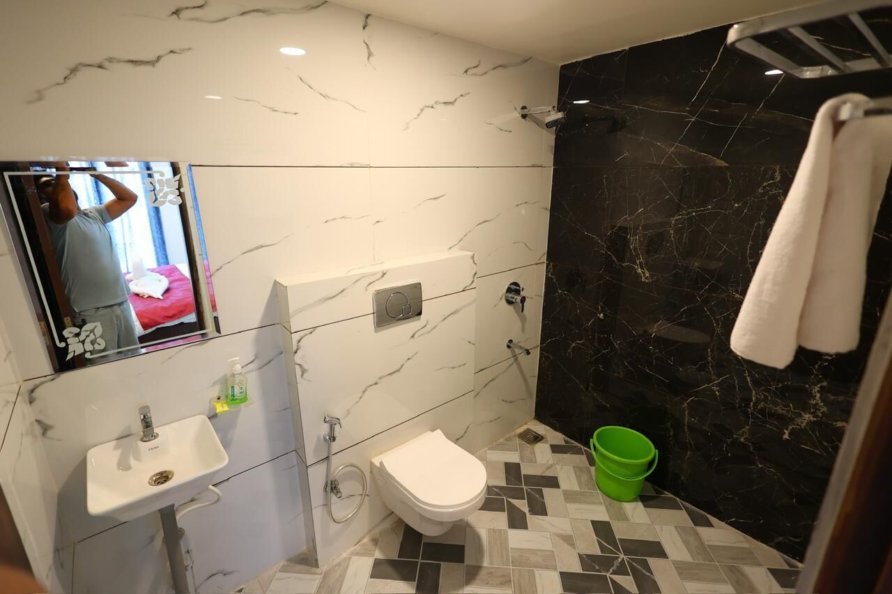 A bathroom with a marble sink, toilet, and a black marble shower wall.