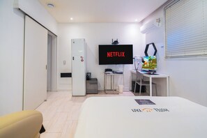 Une chambre d’hôtel moderne équipée d’un lit, d’une télévision, d’un bureau et d’un réfrigérateur.