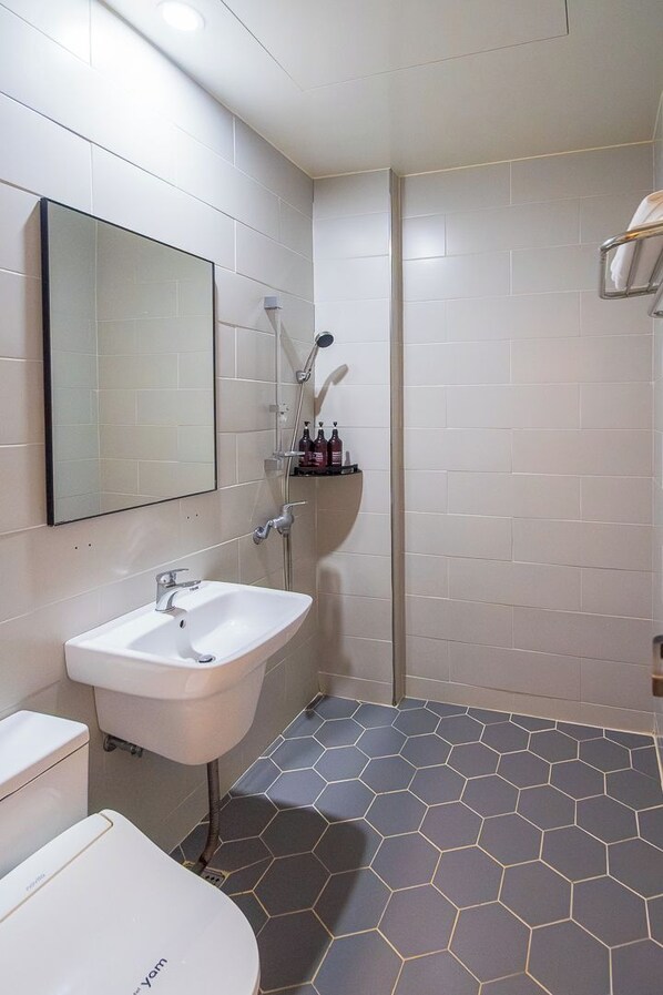 Un baño con lavamanos, espejo y ducha blancos.