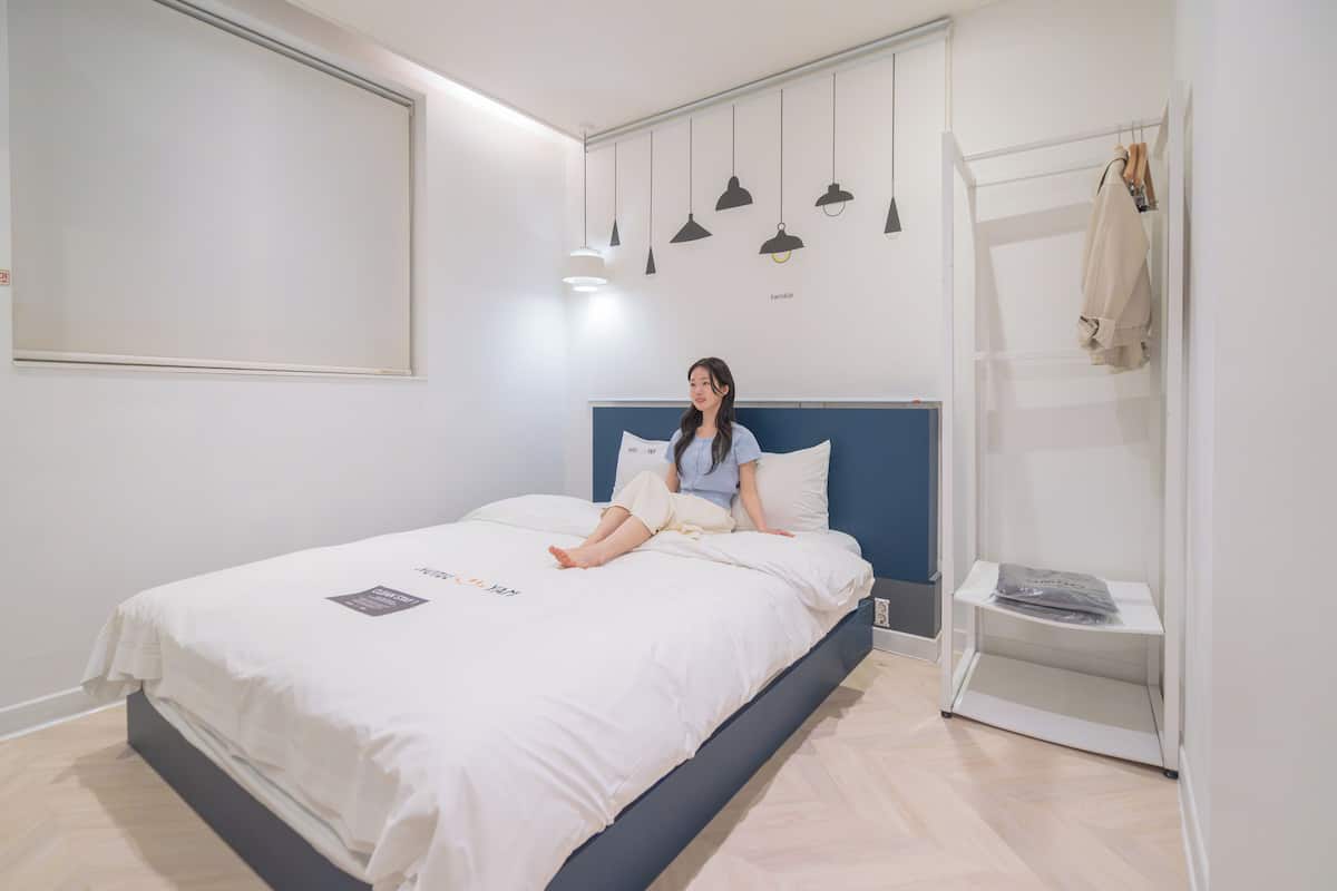 Un dormitorio moderno con cama, mesita de noche, estante en la pared y perchero.