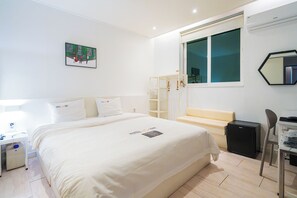 Una habitación de hotel con una cama, un escritorio, una silla, un armario, una ventana y un cuadro en la pared.