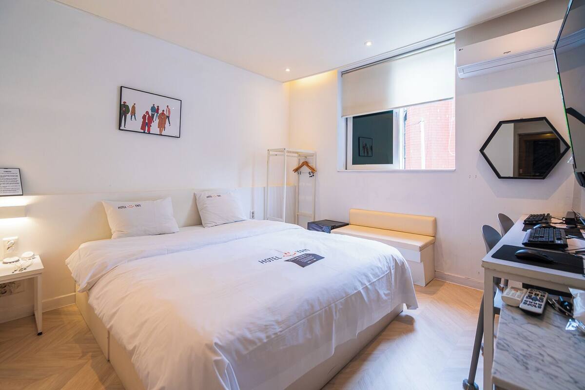 Habitación de hotel con cama, mesita de noche, escritorio y silla.