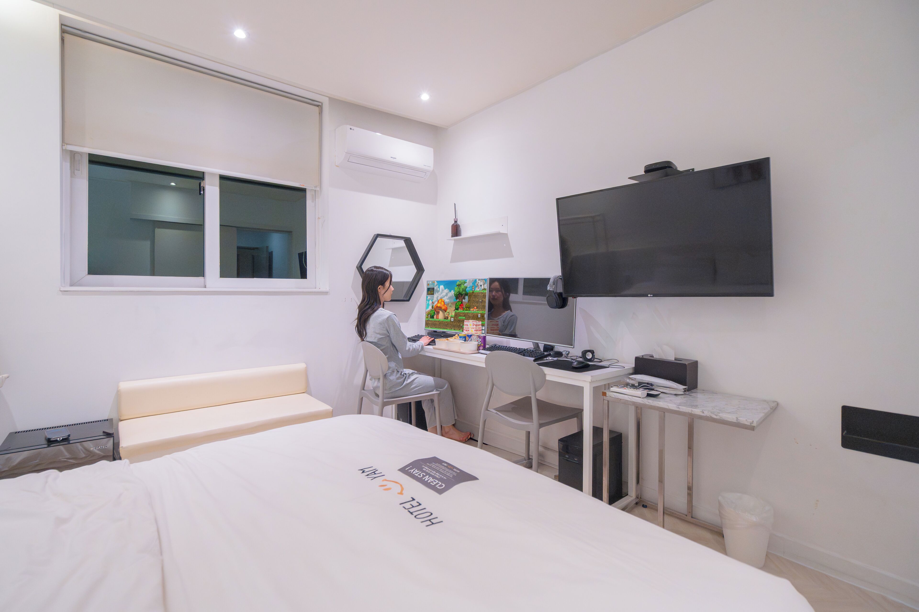 A modern hotel room with a bed, desk, chair, TV, and a window.