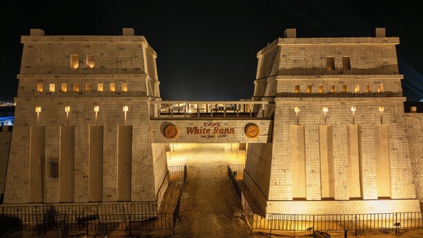 A large stone archway with the inscription "EVOKE White Rann THE TEMPT CITY" and a pathway leading through it. - White Rann - The Tent City (Dholavira)