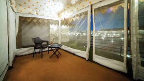 A tented room with a view of a cityscape, a chair, and a table. - White Rann - The Tent City (Dholavira)