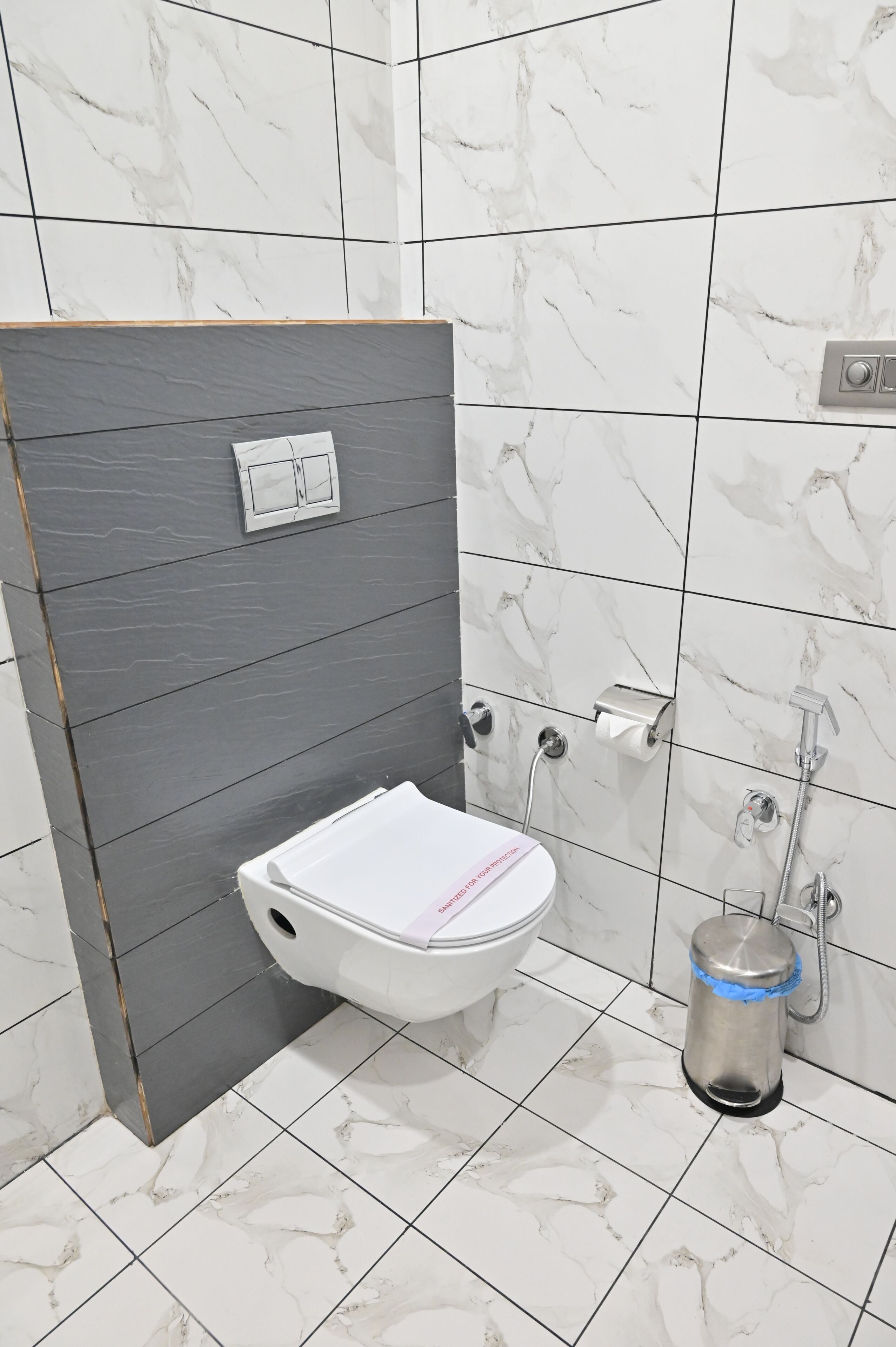 A bathroom with a toilet, a hand dryer, and a paper towel dispenser.