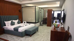 A modern hotel room with a large bed, a desk, and a seating area. - Hotel Devaan (Bathinda)