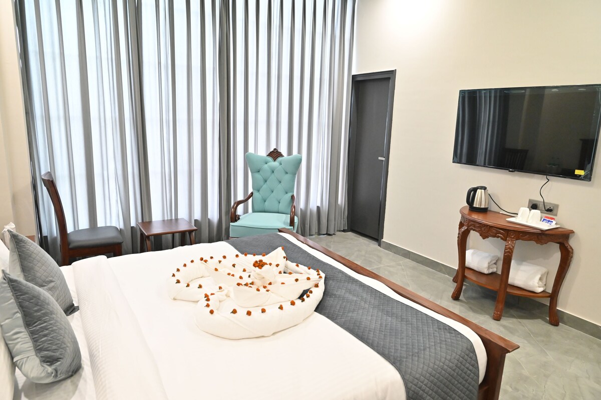 Ein Hotelzimmer mit Bett, Stuhl, Fernseher und Tisch mit Wasserkocher und Tassen.