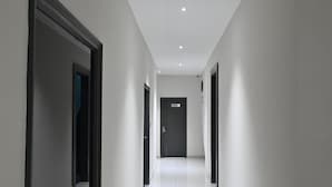 A modern, narrow hallway with white walls and dark door frames, leading to a door labeled "STORE". - Hotel Devaan (Bathinda)