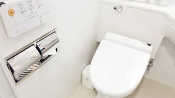 A modern bathroom with a toilet, a toilet paper dispenser, and a control panel with Japanese text.