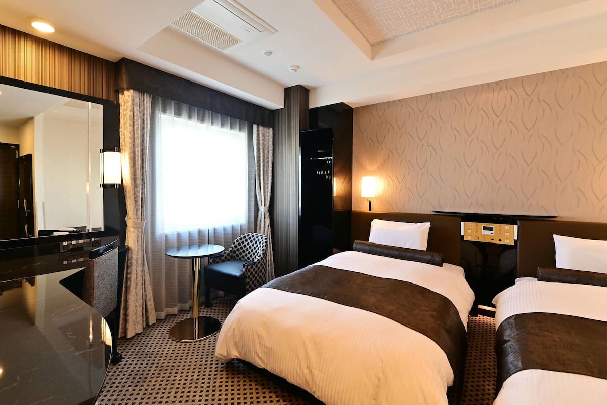Een hotelkamer met een groot bed, een bureau, een stoel, een televisie en een lamp.