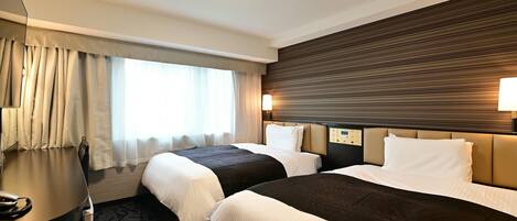 Una habitación de hotel con dos camas, un escritorio, una lámpara y una ventana con cortinas.
