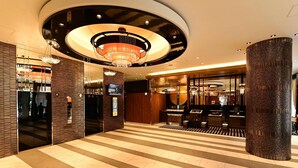 Un hall d’hôtel doté d’un magnifique lustre, d’un comptoir d’accueil et d’un design moderne, avec un sol à rayures.