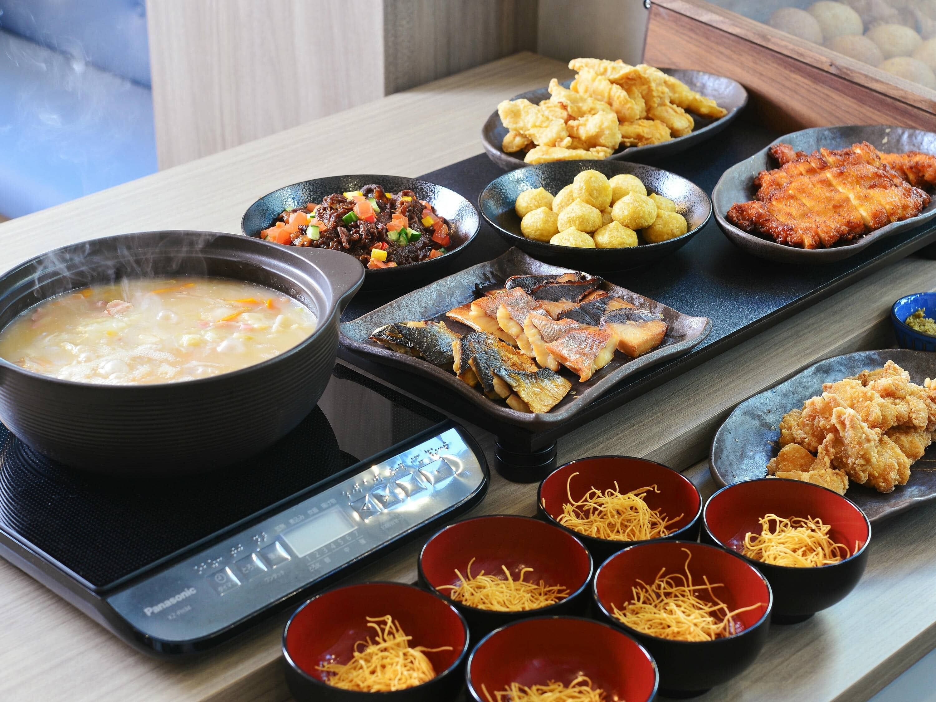 Variedad de platos, incluyendo un tazón de sopa, pescado frito y otros alimentos, sobre una mesa con una balanza digital.