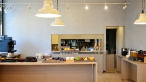 Un café moderne avec un comptoir central, plusieurs machines à café et un large choix de plats et de boissons.