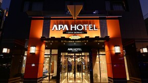 L’extérieur de l’hôtel APA présente un design moderne, avec une entrée imposante et une enseigne lumineuse bien visible.