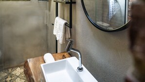 A bathroom with a wooden vanity, a white sink, a mirror, and a shower area. - Refugio Montevale - Cabana da Palmeira (Passo do Sobrado)