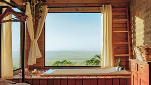 A wooden room with a bed, a window with curtains, and a view of the countryside. - Refugio Montevale - Cabana da Palmeira (Passo do Sobrado)