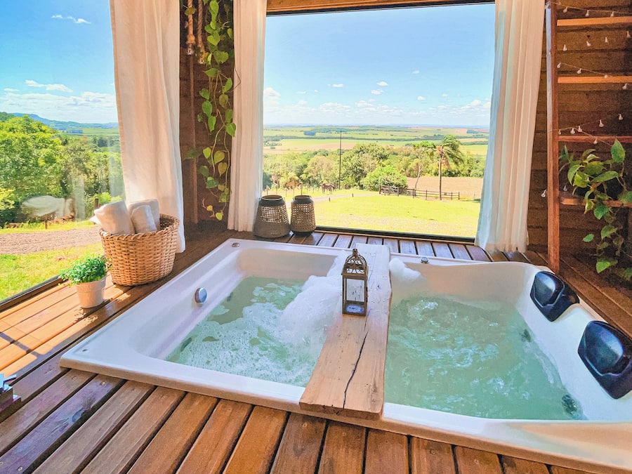 Una cabaña de madera con una bañera grande y vistas al campo.