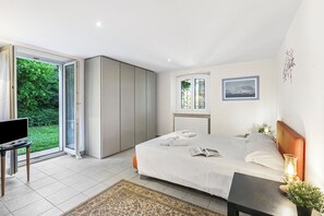 A bedroom with a bed, a TV, a window, and a view of greenery outside.