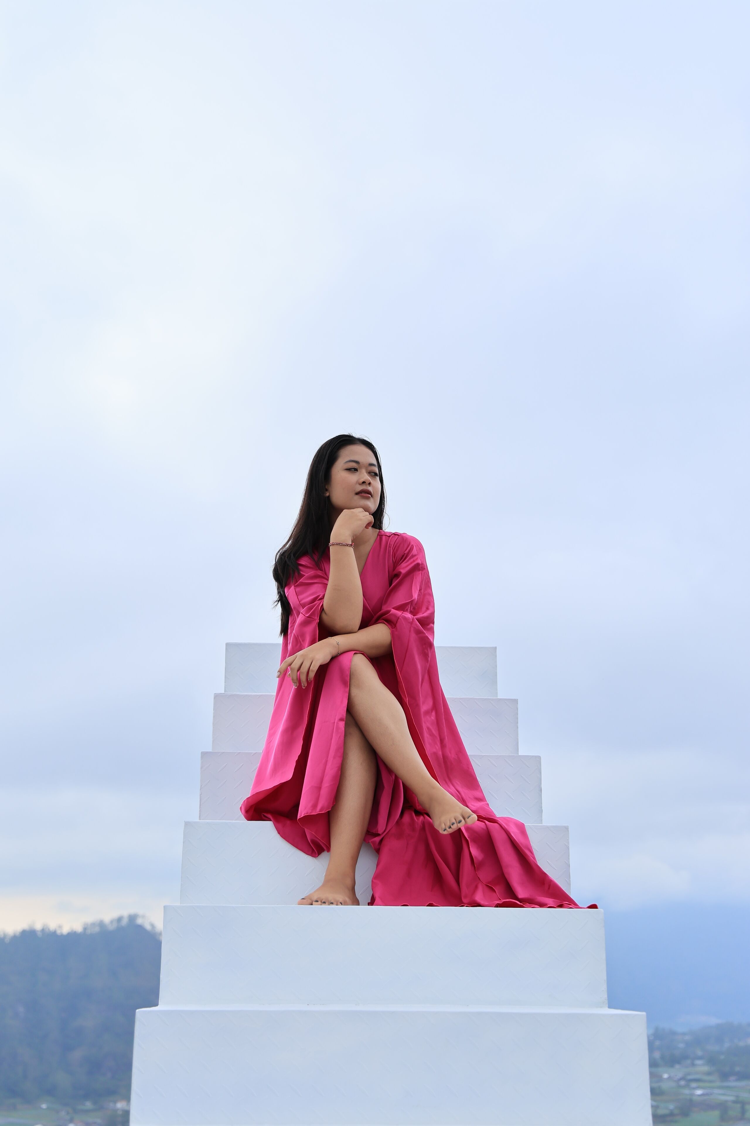 A person sitting on a white staircase with a scenic view in the background.